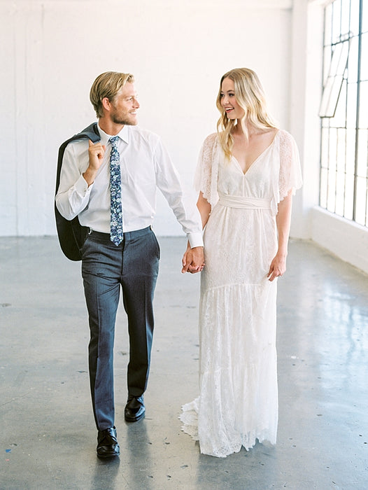 A couple in wedding attire holding hands and walking through the bright, airy space of Apex Photo Studios in Downtown Los Angeles, exuding elegance and joy