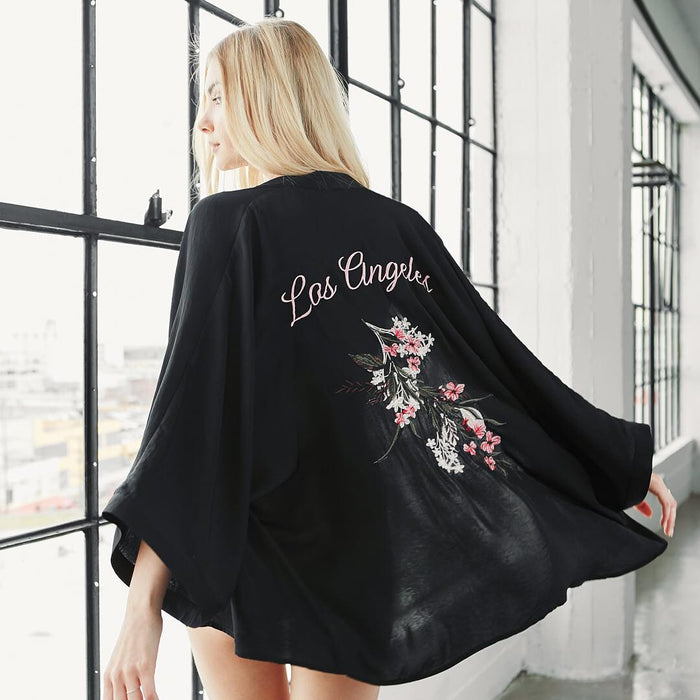 Blonde model showcasing a Los Angeles-themed black kimono with floral embroidery at Sunrise Studio, Apex Photo Studios' Studio D
