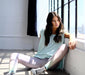 Relaxed young woman in casual attire sitting by the window at Sunrise Studio, Apex Photo Studios' Studio D, enjoying the natural light