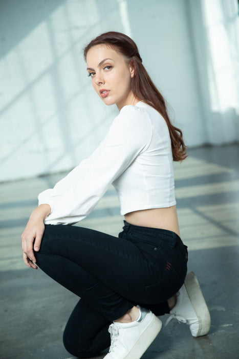 Fashionable woman in a white crop top and black jeans posing in the natural light at Sunrise Studio, Apex Photo Studios' Studio D