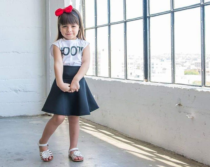 Young girl with a red bow smiling in natural light at Sunrise Studio, Apex Photo Studios' Studio D