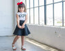 Young girl with a red bow smiling in natural light at Sunrise Studio, Apex Photo Studios' Studio D