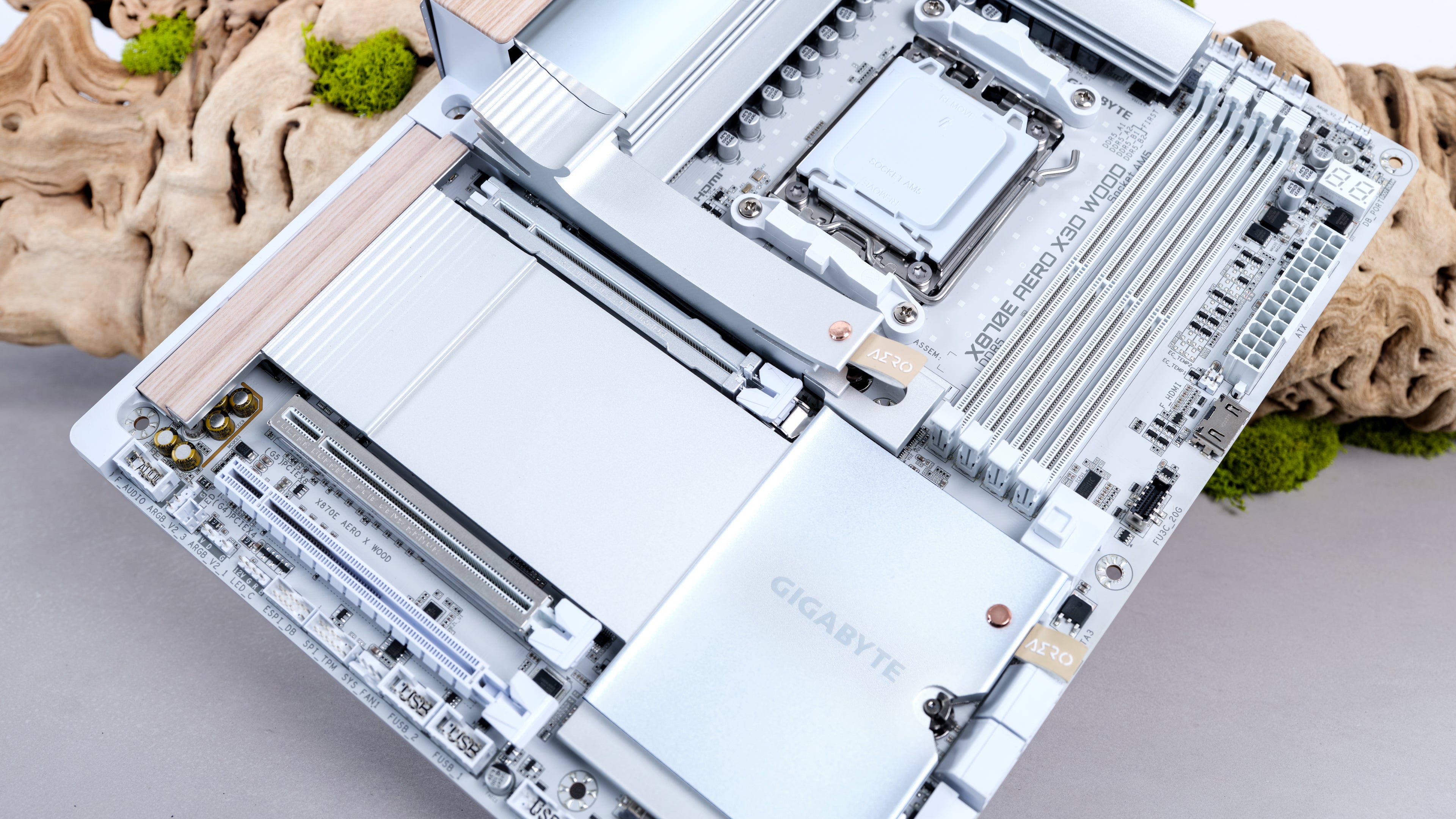 apex photo studios close up of X870E AERO X3D WOOD Computer motherboard on a light gray surface with decorative elements