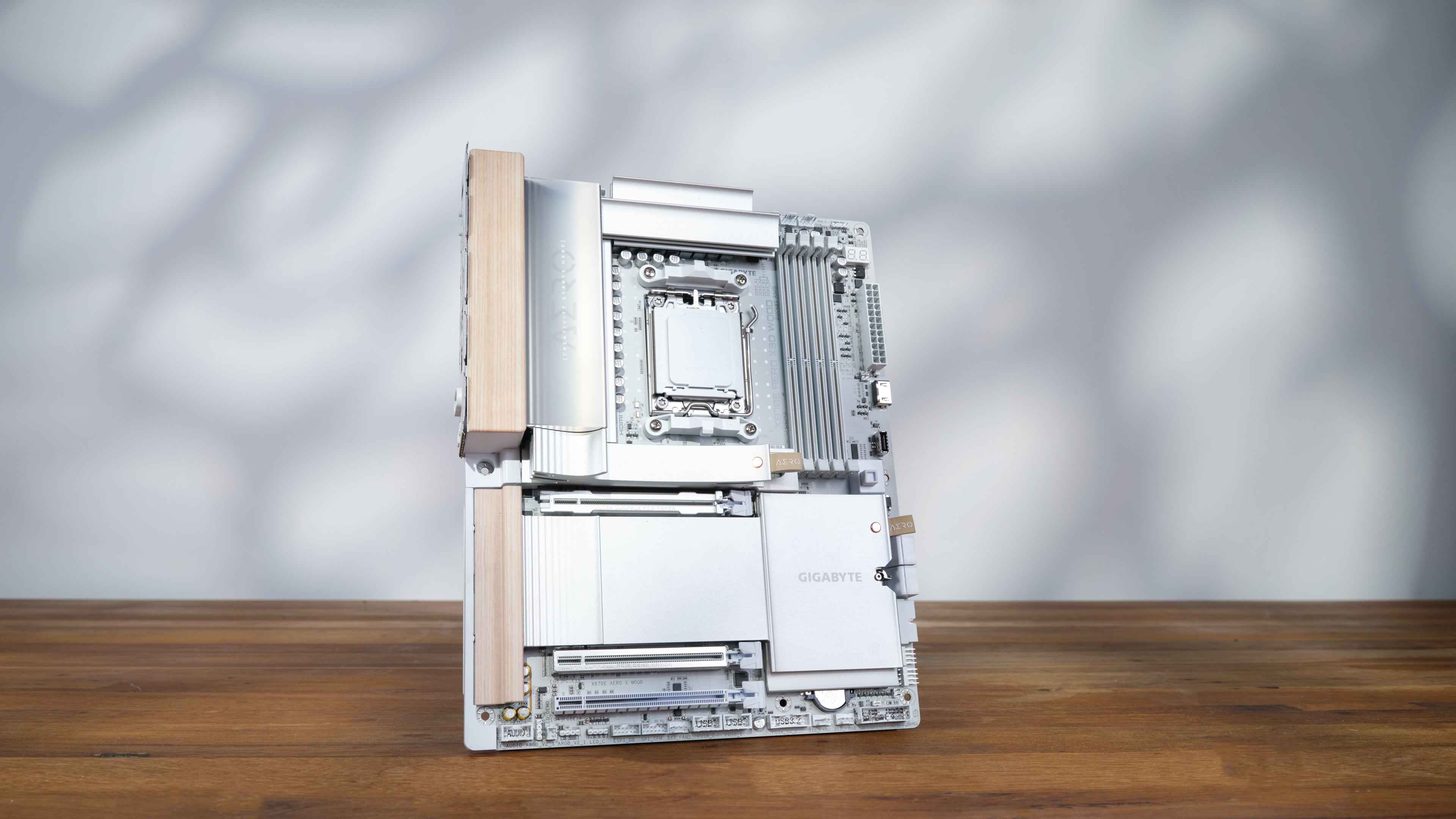 X870E AERO X3D Wood motherboard on a wooden surface on white background with soft leaf lighting pattern apex photo studios