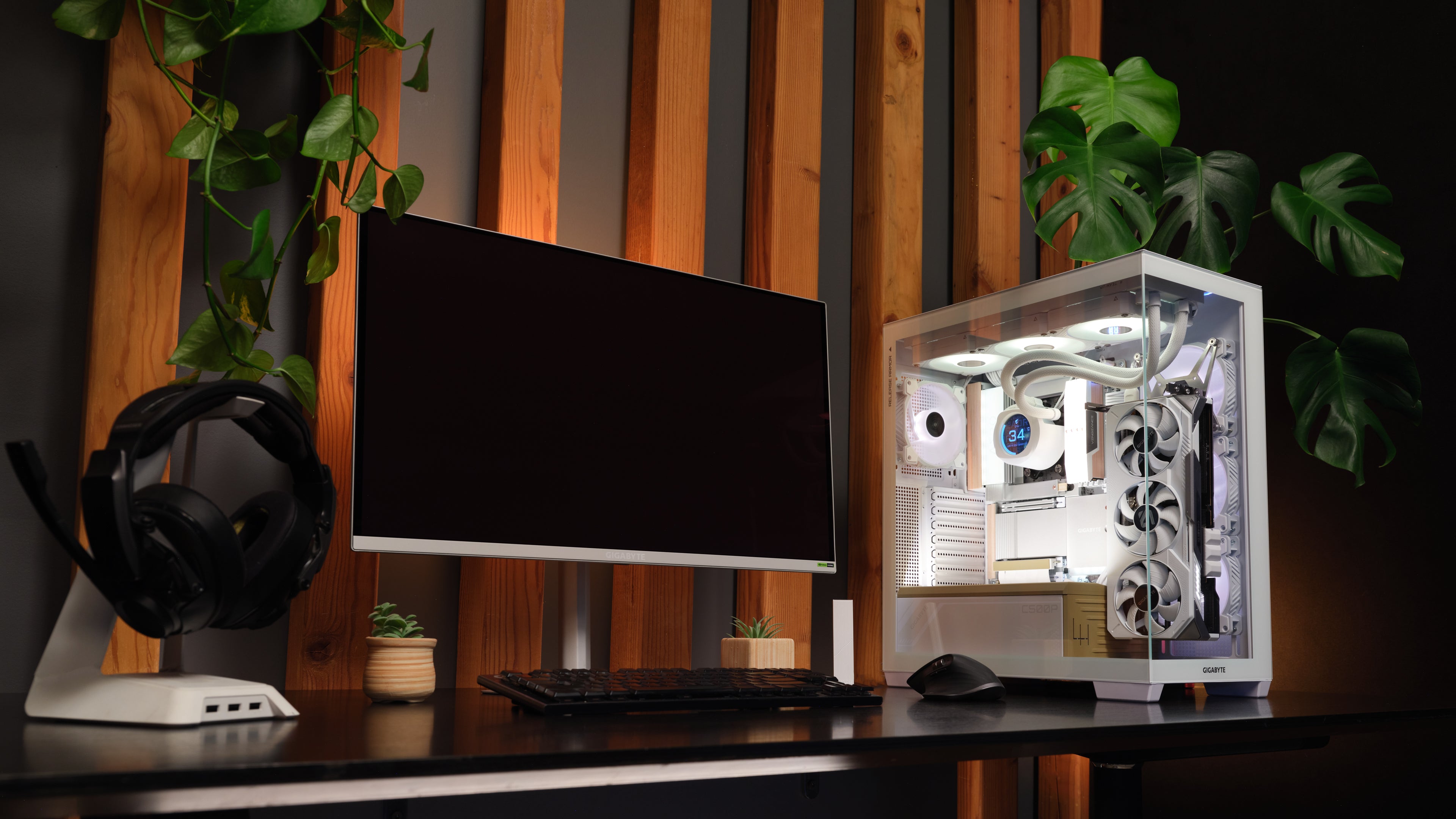 apex photo studios Modern desk setup with a computer monitor, keyboard, and transparent gaming PC case with GIGABYTE X870E AERO X3D wood motherboard inside